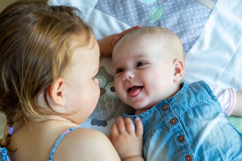 Twee zussen die naar elkaar lachen Jij en ik fotografie Apeldoorn