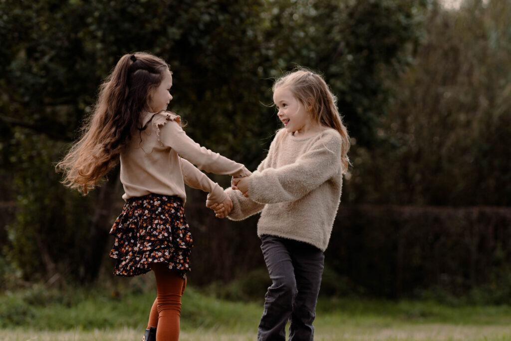 Twee zussen spelen samen tijdens een fotoshoot in de natuur in de omgeving van Apeldoorn
