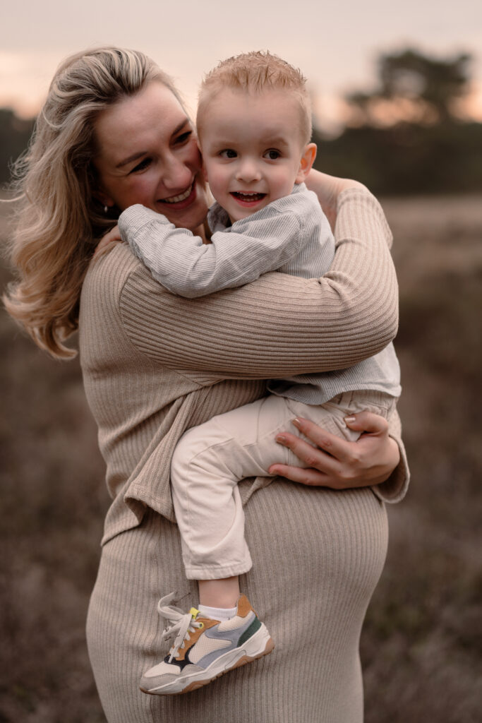 een zwangere mama knuffelt haar zoontje tijdens een zwangerschapsshoot in de omgeving van Apeldoorn