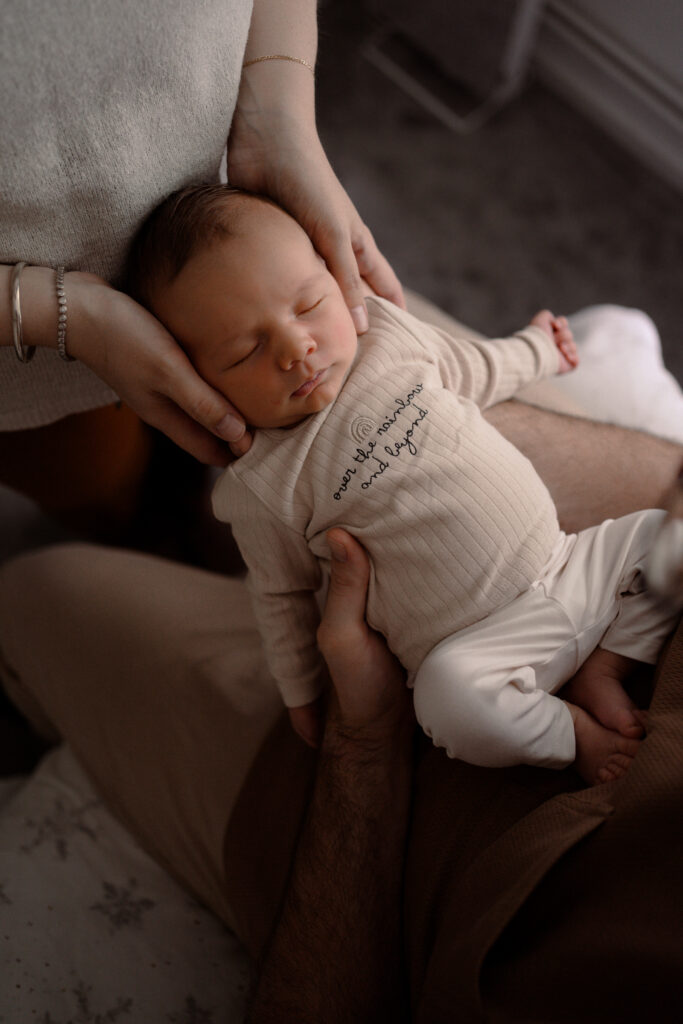 Baby zit tussen papa en mama aan en wordt liefdevol geknuffeld