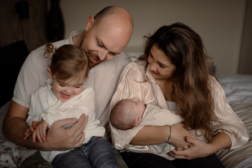 Gezinnetje die plezier maakt op bed tijdens een newbornshoot aan huis Apeldoorn
