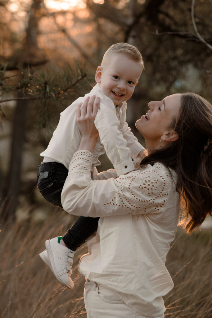 Moeder en zoon lachen samen tijdens een fotoshoot in de omgeving van Apeldoorn