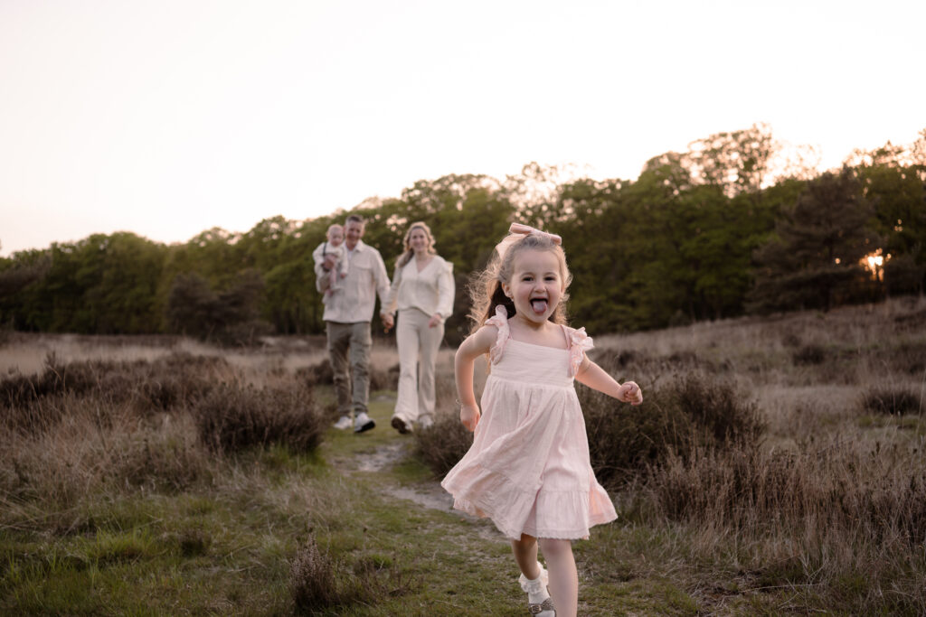 Dochter rent voor haar ouders uit vol enthousiasme over de heide in de omgeving van Apeldoorn