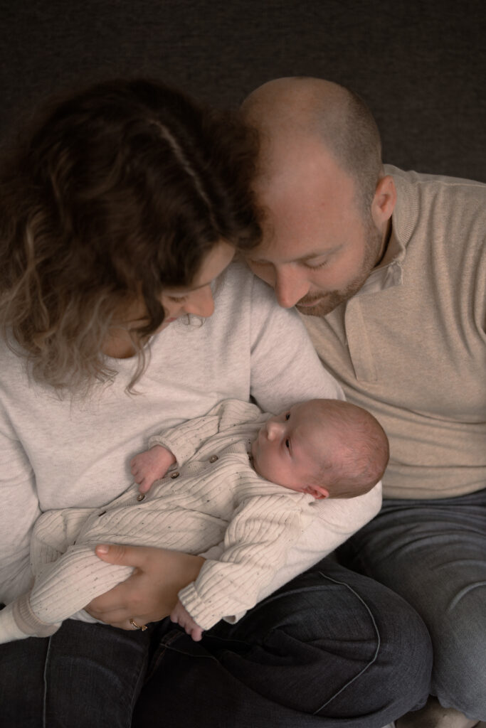 Vader en moeder met hun pasgeboren zoontje op de arm van moeder tijdens een newbornshoot Apeldoorn door Joenne Bokhorst Fotografie