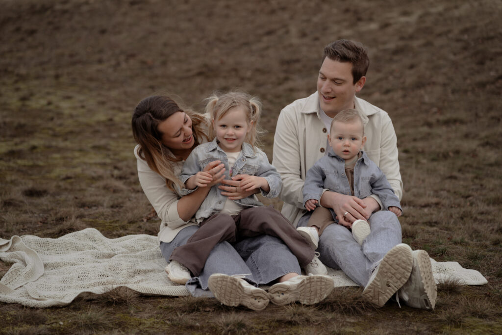 Gezin met peuter en baby zittend op een kleed tijdens een gezinsfotoshoot op de Veluwe door fotograaf Joenne Bokhorst fotografie