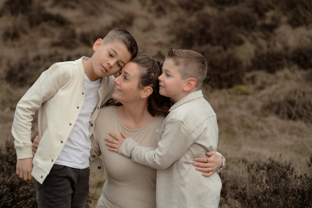 Moeder met twee zoons die haar omhelzen tijdens een gezinsshoot op de Veluwe, gefotografeerd door fotograaf Joenne Bokhorst fotografie in Apeldoorn