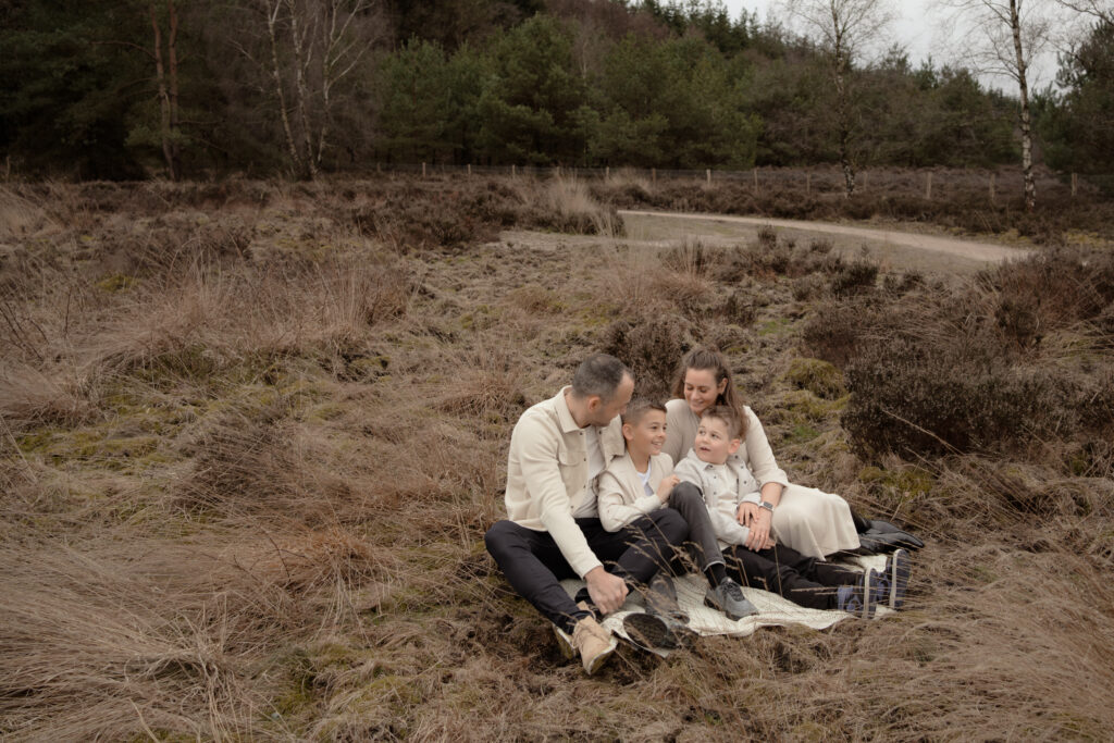 Gezin met twee kinderen zittend op de heide tijdens een gezinsfotoshoot, fotograaf Joenne Bokhorst fotografie Apeldoorn 